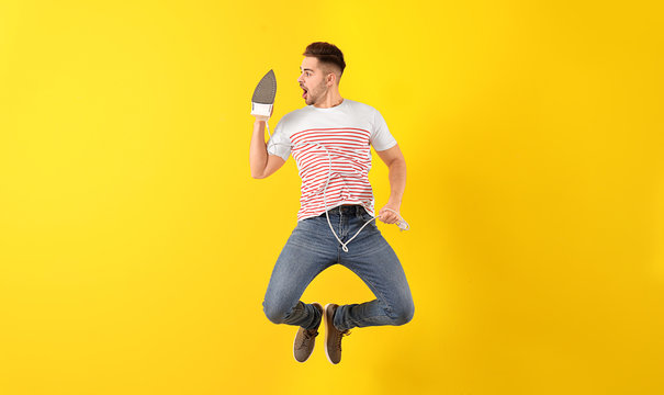 Jumping Young Man With Iron On Color Background
