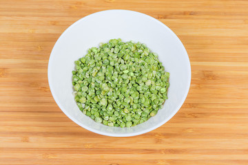 Green split peas in bowl on a wooden surface