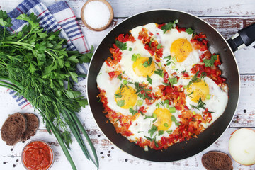 Shakshouka with five cooked eggs on top of tomato sauce in cast iron skillet	