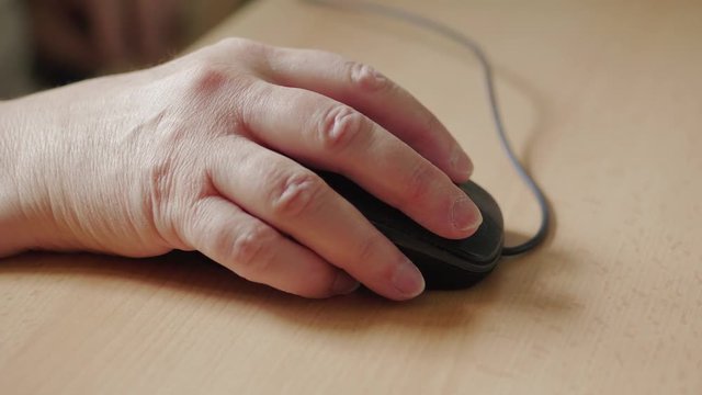 Senior woman's hand clicking on mouse, work on computer, browsing internet. Grandmother at workplace in office, left-clicking. Elder lady working on laptop. Lifestyle of aged. Grandma using technology