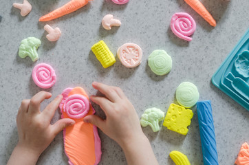 Child's hands with colorful clay.  ice cream, fruits and vegetables from plasticine.  Pastel color plasticine. Homemade clay. Close up