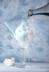 Preparing of tasty cotton candy cocktail on blue background