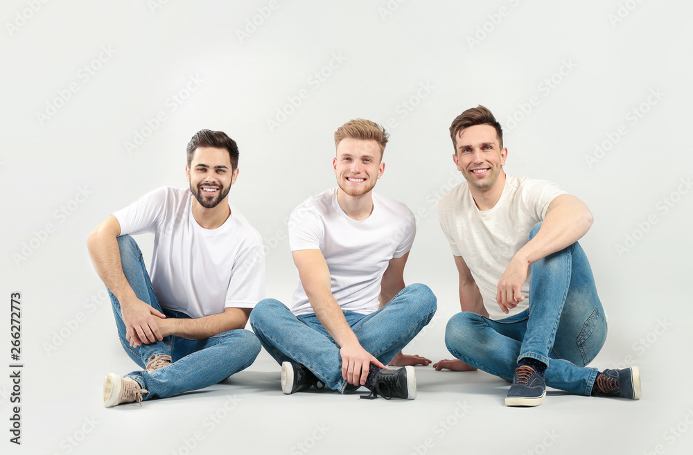 Wall mural Handsome young men on light background