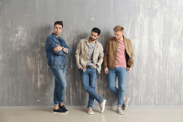 Fashionable young men near grey wall