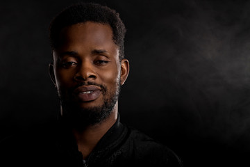 Portrait of handsome young African man on black background