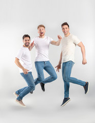 Jumping young men on light background