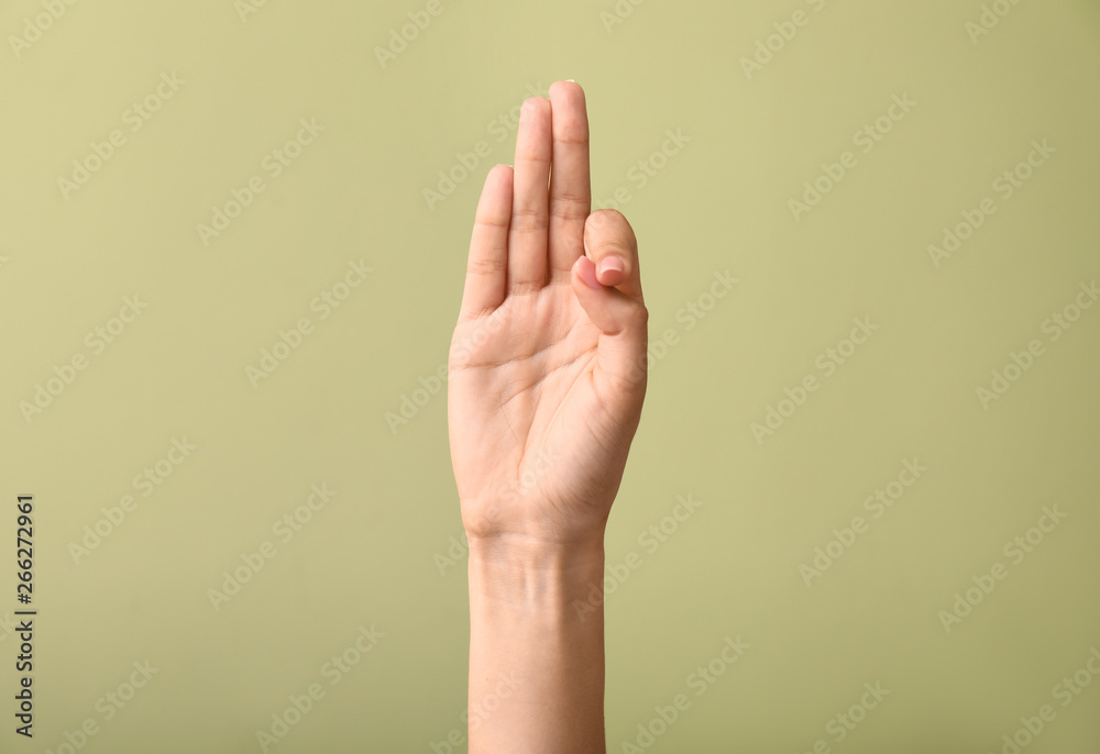 Wall mural female hand showing letter f on color background