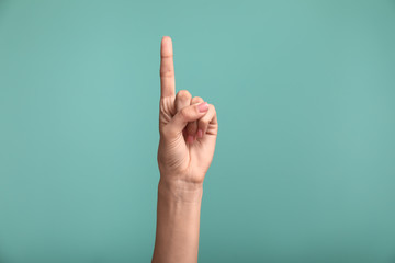 Gesturing female hand on color background - obrazy, fototapety, plakaty