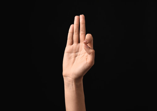 Female hand showing letter F on dark background