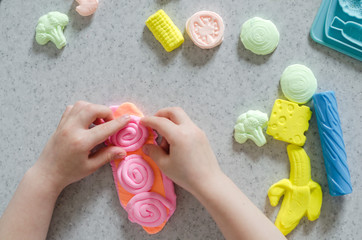 Child's hands with colorful clay.  ice cream, fruits and vegetables from plasticine.  Pastel color plasticine. Homemade clay. Close up