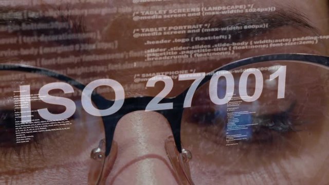 ISO 27001 text on the background of female software developer. Eyes of woman with glasses are looking at programming network code space abstract technologies connecting global data network