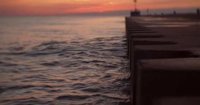 Slow motion waves gently lapping edge of pier during the final stages of sunset