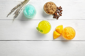 Different body scrubs on white wooden background