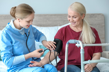 Obraz premium Medical assistant measuring blood pressure of mature patient at home
