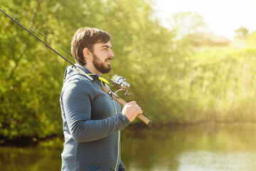 a man on a Sunny day goes fishing, holding a fishing rod on his shoulder