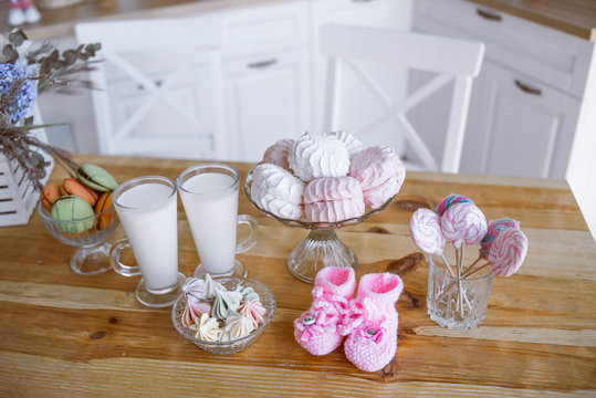 milk, marshmallows, sweets, children's shoes on the kitchen table, decor for a photo session of pregnancy
