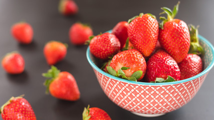 Delicious strawberries in a bowl on black background.