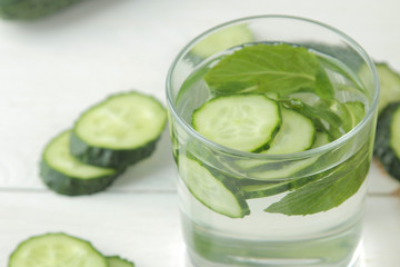 water with cucumber. Refreshing diet water with cucumber in a glass cup on a light background. detox drink concept. summer refreshing drink. close-up