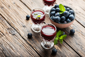 Sweet blueberry liqueur on the wooden table