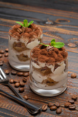 two portions Classic tiramisu dessert in a glass on wooden background