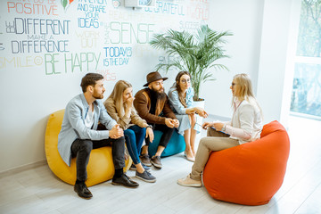 Two young couples sitting during the psychological therapy with psychologist, solving some mental...