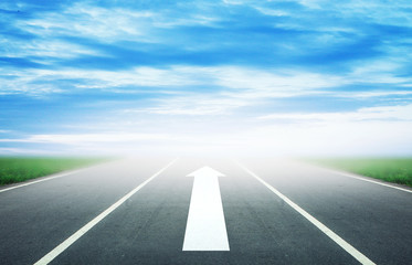 Background of blurred asphalt road, clear blue sky with clouds. Sunlit skyline