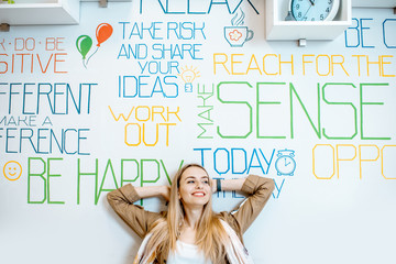 Portrait of a young smiling woman on the wall background with various inscriptions on the topic of mental health indoors
