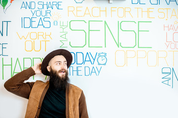 Portrait of a stylish bearded man on the wall background with various inscriptions on the topic of mental health indoors