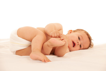 Hapy baby boy in playing on bed isolated over white