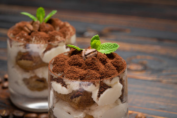two portions Classic tiramisu dessert in a glass on wooden background