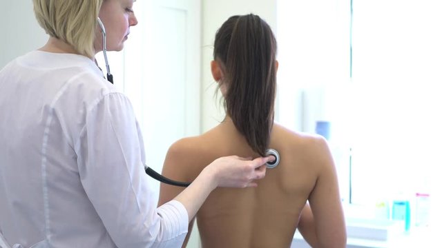 therapist listening to the back of the patient with a stethoscope