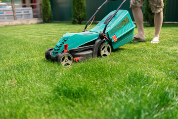 Lawn mower in the work on the plot with green grass