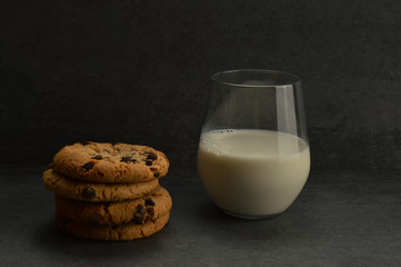 A glass of milk and chocolate cookies on the gray rustic stone background