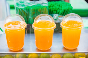Rows of plastic cups with orange Juice.