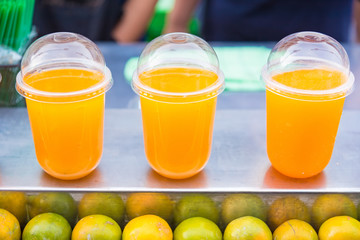 Rows of plastic cups with orange Juice.