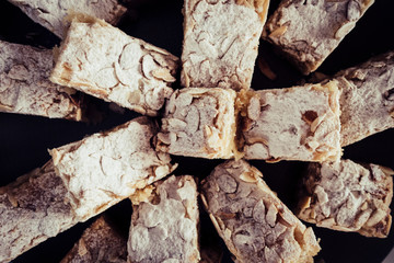 Cakes portrion with nuts and white powder sugar on a black plate viewed from above - party event celebration food concept