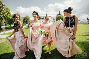 Happy beautiful bride and bridesmaids posing outside.