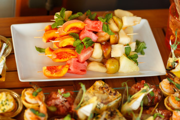 Fruit canapes from peach, watermelon and pear. Fruits on skewers.