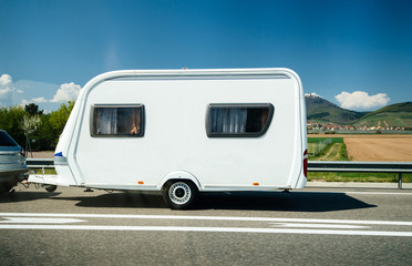 New RV trailer motorhome carried by a gray car on French highway travel towar great holidays with clear sky and green fields