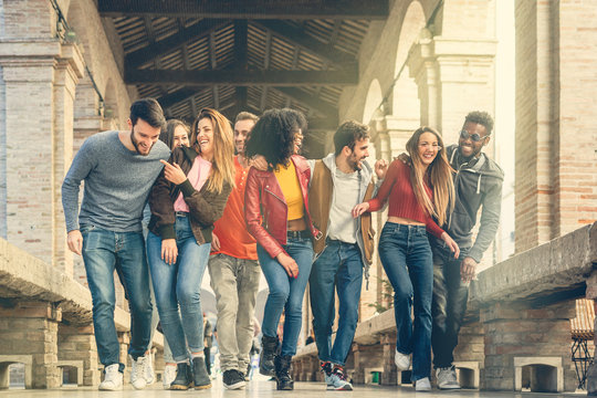 Group Of Multiracial Young People Walking Outdoors While They're Joking And Having Fun Together