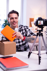 Smiling short-haired man unpacking new innovative orange tablet