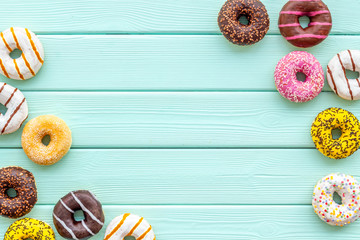 Donuts of different flavors for breakfast on mint green wooden background top view space for text