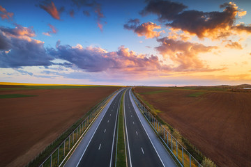 Aerial view of highway on sunset. Transportation background. Landscape with road near countryside fields