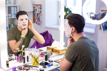 Accurate man correcting his smoothing face mask while getting ready