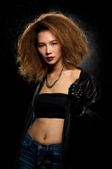 Fototapeta premium Fashion Asian Woman Tan skin Afro fu hair eyes beautiful make up black bra jacket silver necklace posing, Studio Lighting Dark Background back rim light with steam smoke effect