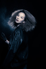 Fototapeta premium Fashion Asian Woman Tan skin Afro fu hair eyes beautiful make up black bra jacket silver necklace posing, Studio Lighting Dark Background back rim light with steam smoke effect