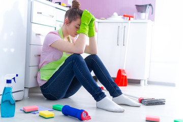 Tired overworked cleaning woman feeling fatigue of busy day and cleaning house at kitchen at home