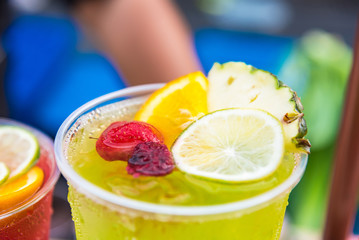 Healthy water with ice lemon raspberries mint leaf bubbles and surrounded with green nature and trees into the background.