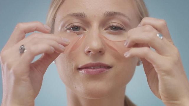 blonde model during facial treatment routine. Take an eye pathces away. Undereye treatment
