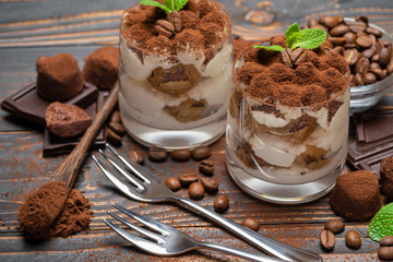 two portions Classic tiramisu dessert in a glass on wooden background